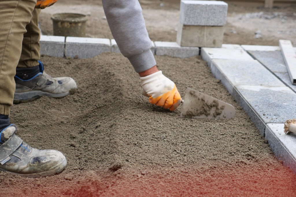 Professionelle Pflasterarbeiten: Handwerker bereitet Untergrund für Gehwegplatten vor.